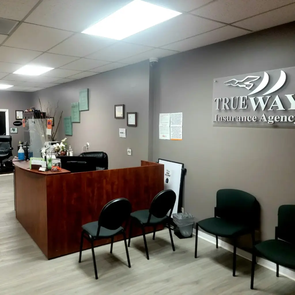 Reception area inside True Way Insurance Agency with the brushed metal Trueway Insurance Agency wall sign and framed certificates